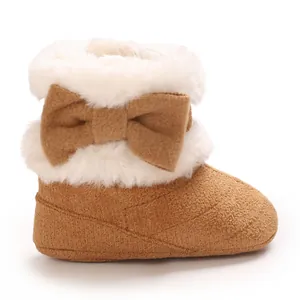 Vue latérale de bottes bébé marron avec fausse fourrure blanche et nœud