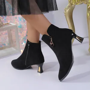 Detail view of stylish black suede pointed-toe ankle boots with unique gold-detailed mid-heels.