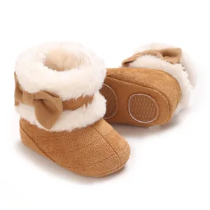 Vue détaillée de bottes de neige marron pour bébé avec nœud et fausse fourrure.