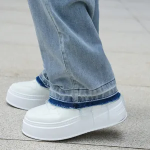 Close-up detail of straight leg jeans with frayed dark blue hem and white platform shoes