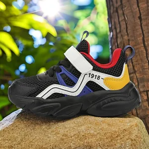 Breathable mesh boys' athletic sneakers with '1918' print and white strap on a rock