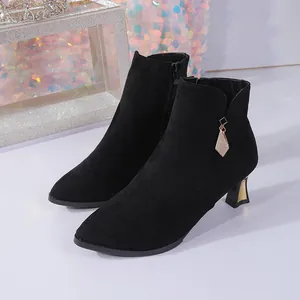 Close-up detail of elegant black suede ankle boots with pointed toe and gold-accented heel