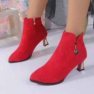 Detail of red pointed-toe kitten heel ankle boots with elegant decorative charm.