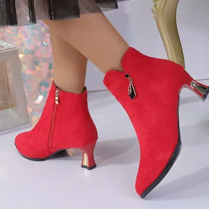 Detail of red suede pointed-toe ankle boots with unique kitten heels and side zipper.