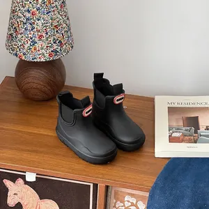 Detailed view of black waterproof children's rain boots in a cozy lifestyle setting