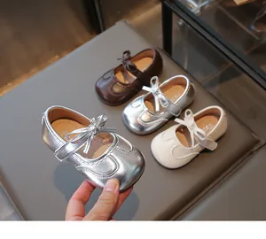 Dettaglio di ballerine Mary Jane per bambina con fiocchi in argento, bianco e marrone