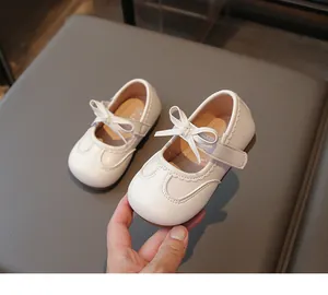 Vista dettagliata delle scarpe bianche da principessa per bambine con fiocco e smerlo.
