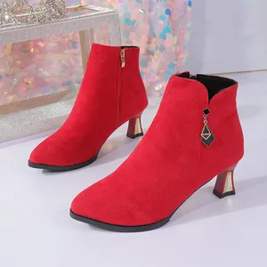 Detail of red suede pointed-toe ankle boots featuring a gold-tone zipper and charm