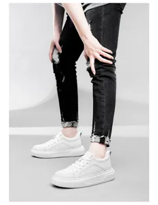 Primo piano di sneakers bianche platform con suola da 6 cm e jeans strappati.