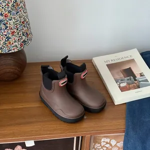 Detail shot of brown waterproof children's marting boots arranged on a wooden table