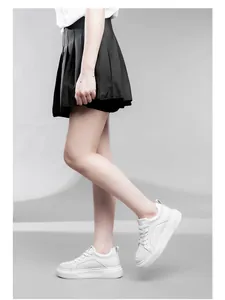 Vista laterale di eleganti sneakers bianche con plateau da 6 cm indossate da una modella