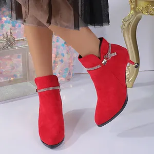 Close-up of elegant red suede pointed-toe ankle boots with rhinestone strap detail.