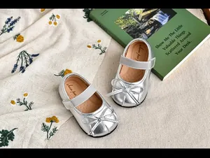 Vista detallada de zapatos de princesa plateados para niña con un lazo elegante
