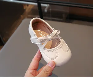Primo piano di scarpe Mary Jane bianche da bambina con fiocco e bordi a onde