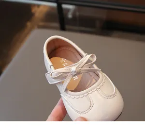 Dettaglio di scarpe Mary Jane color crema per bambina con fiocco e bordi a onde.