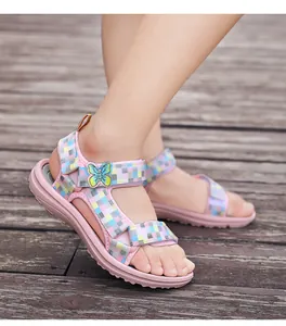 Close-up of pink girls' sandals with butterfly ornament and checkered straps on wooden deck