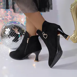 Black pointed-toe ankle boots with sculptural heel and heart buckle detail.