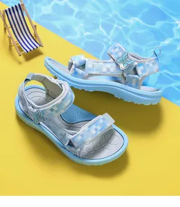 Stylish blue girls sandals with butterfly detail on a creative summer beach background