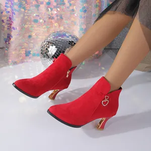 Detailed close-up of red suede pointed-toe ankle boots with gold heels and heart charms