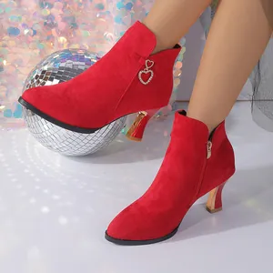 Detail of red suede pointed-toe ankle boots with decorative heart charm