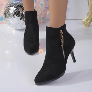 Detailed view of elegant black suede pointed-toe ankle boots with gold-tone side zipper detail
