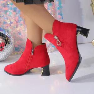 Primer plano de elegantes botines de gamuza roja con punta y tacón medio en modelo.