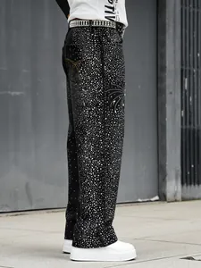 Vue latérale de jeans en denim noir avec strass denses et une ceinture en cristal assortie.