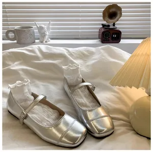 Macro view of silver girls' Mary Jane princess shoes with ruffle socks on white cloth