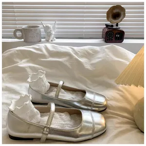 Silver metallic girls Mary Jane shoes styled with white lace socks on white bedding.