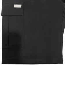 Close-up of side flap pocket on black cotton twill cargo shorts for men.