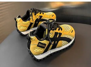 Close-up view of children's breathable yellow and black mesh sports sneakers with chunky soles