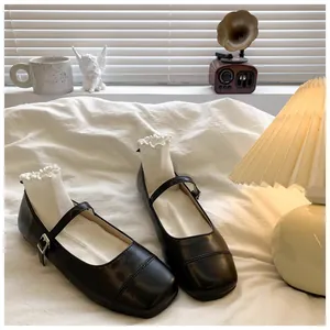Detail view of black girl's Mary Jane shoes on white bedding with warm lamp light.