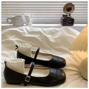 Detailed view of black Mary Jane leather shoes for girls on a cozy white bed.