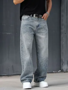 Détail d'un jean droit ample pour homme avec des embellissements en strass brillants.