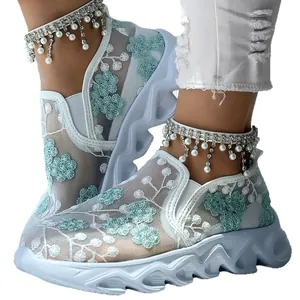 Close-up of white mesh sneakers with green floral embroidery and chunky platform soles