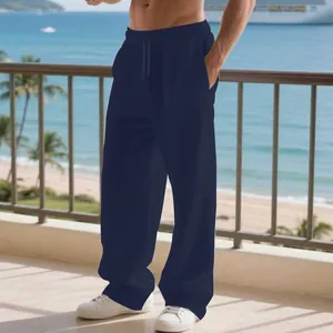 Dettaglio di pantaloni casual in lino blu navy da uomo con coulisse in riva al mare.