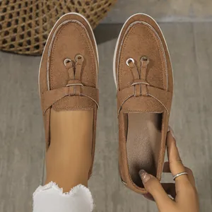 Close-up of brown suede flat loafers featuring decorative metal eyelets and soft soles