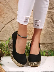 Nahaufnahme schwarzer Slipper-Wedges mit stylischen geflochtenen Plateaus