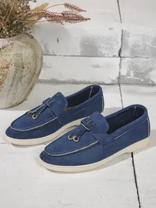 Close-up view of elegant blue suede women's slip-on flats with metallic buckle details