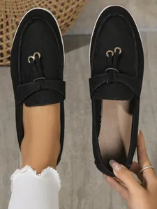 Close-up of women's black suede flat loafers with decorative metal rings and soft sole