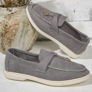 Detail view of stylish grey faux suede women's loafers with flat white sole and buckle