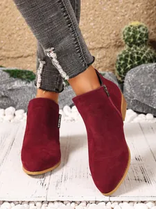 Gedetailleerd overzicht van bordeauxrode suède Chelsea boots met zijrits en puntige neus