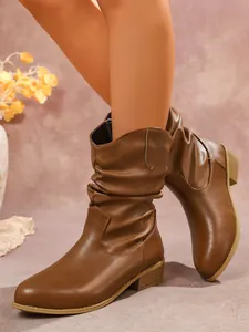 Detalle de botas western marrones con diseño arrugado y tacón grueso muy elegante.