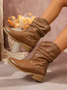 Detalle de botas de media caña marrones para mujer con diseño fruncido y tacón