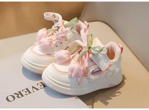 Vue détaillée de baskets blanches pour fillettes avec breloques tulipes et rubans
