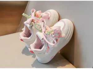 Gros plan de baskets blanches pour filles avec tulipes 3D et rubans roses.