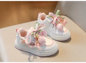 Gros plan de baskets blanches pour filles avec fleurs de tulipes roses et nœuds rubans.