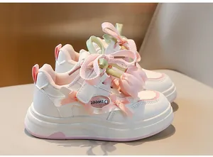 Gros plan de baskets blanches pour filles avec nœuds roses et breloques tulipes