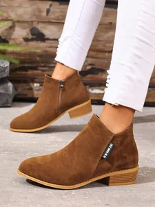 Detail van bruine suède Chelsea boots met spitse neus, zijrits en een stevige blokhak