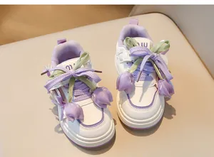 Vue détaillée de baskets blanches pour enfants avec lacets ruban et tulipes violettes.